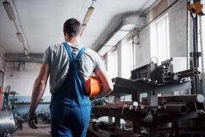 Portrait of a young worker in a hard hat at a large waste recycling factory The engineer monitors the work of machines and other equipment