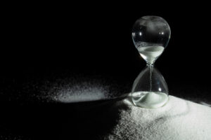 Hourglass add more sand of time on white sand over black backgro