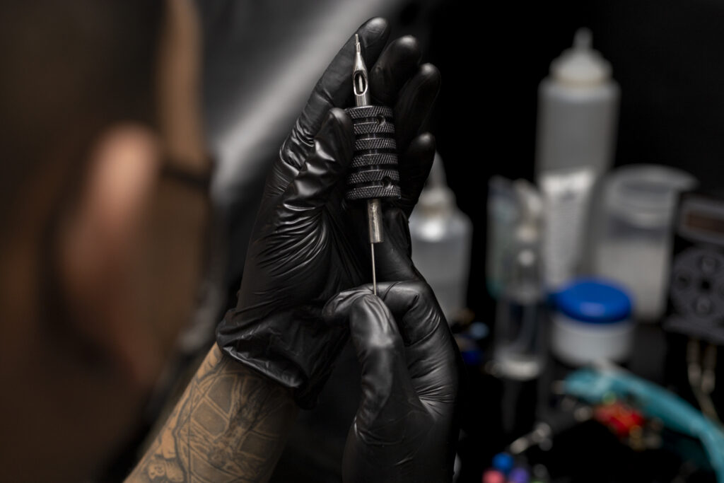 Tattooist assembling the sterilized needle in the grip Wearing black gloves Body art concept