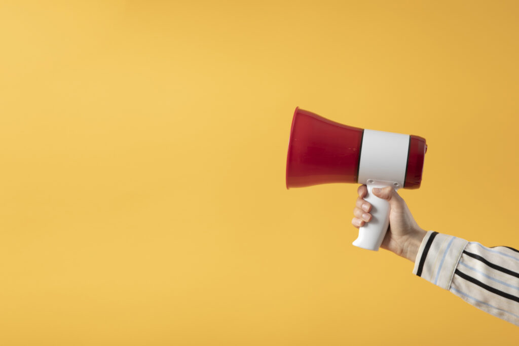 hand holding megaphone with yellow background